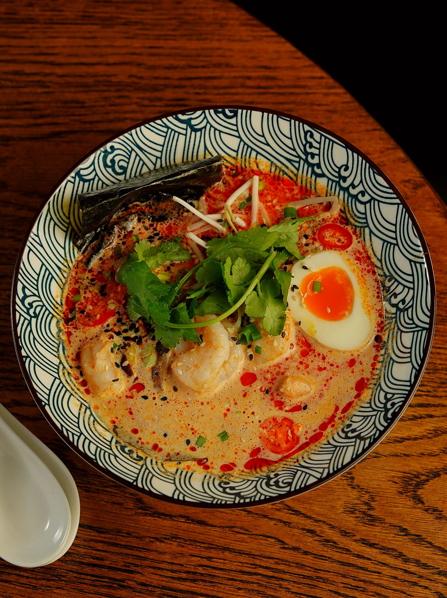 A deep bowl of mayu tonkotsu ramen with chashu and a seasoned egg